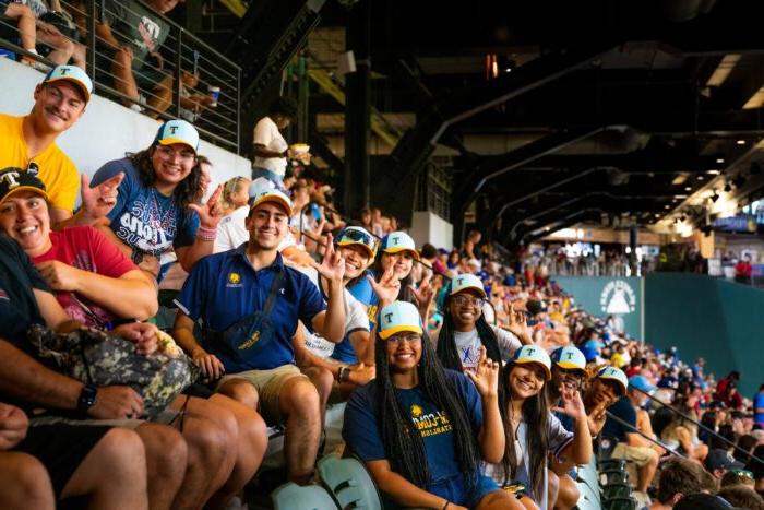 Fans in the stands at a baseball game posing for a photo.